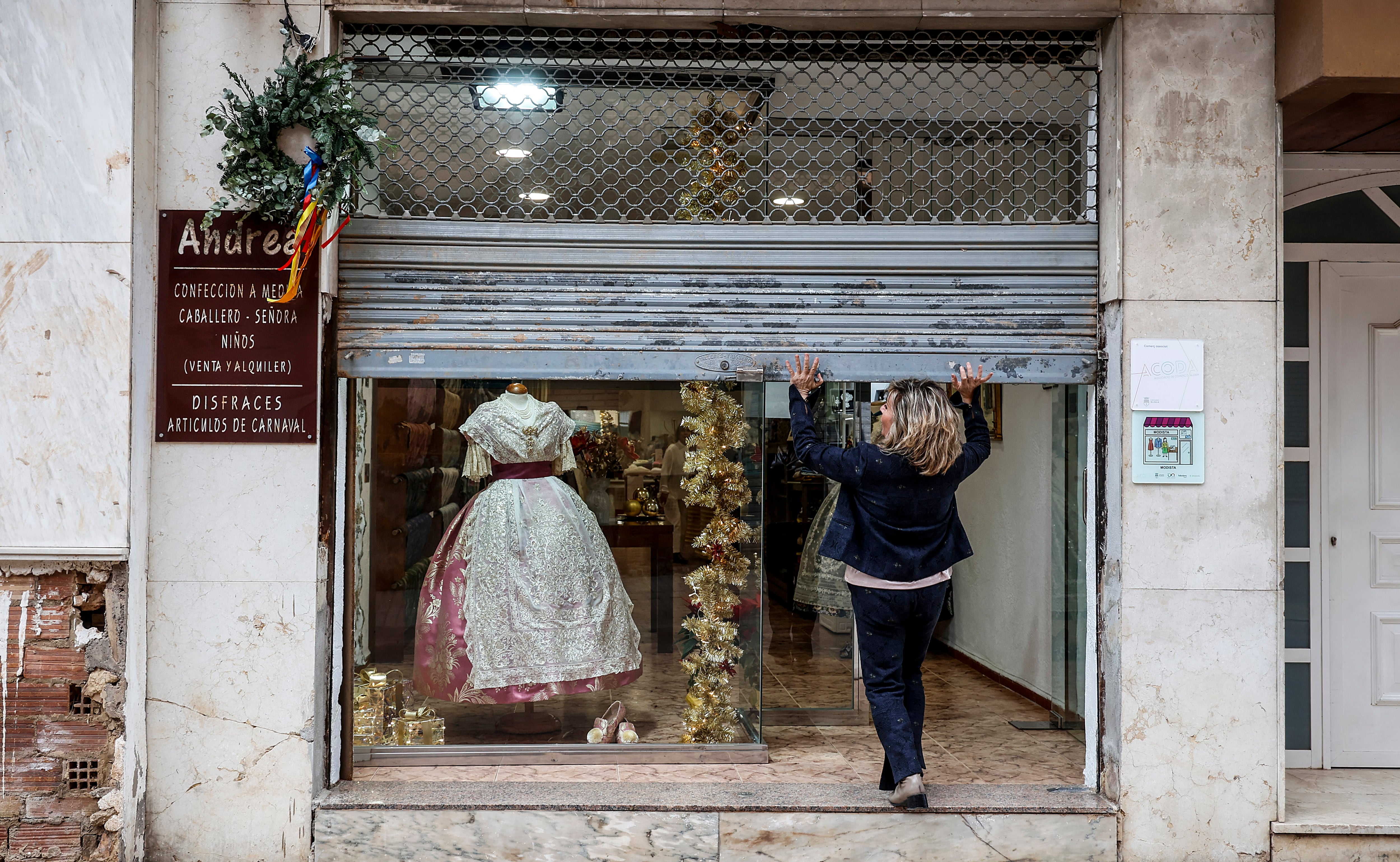 Una mujer reabre su negocio en Aldaia, afectado por las inundaciones, meses después del paso de la Dana en Valencia.