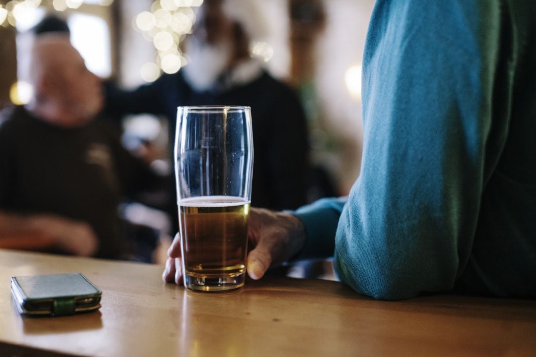 un hombre toma una cerveza en la barra de un bar.