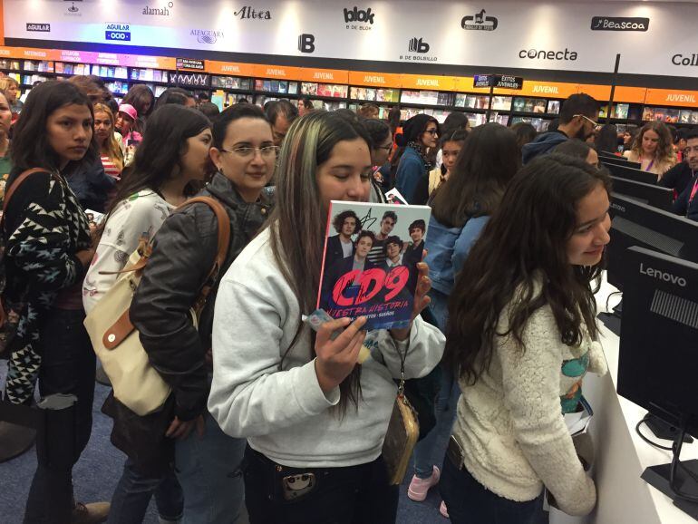 Jóvenes hacen cola frente a las cajas de la editorial Penguin Random House con el libro de CD9 en las manos.