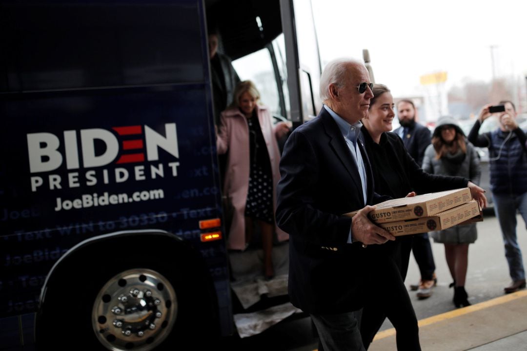 El candidato demócrata presidencial estadounidense de 2020 y exvicepresidente Joe Biden lleva pizza para voluntarios mientras visita una oficina de campaña en Des Moines