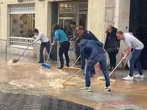 Varias personas achican agua en la calle Burgos de la capital palentina