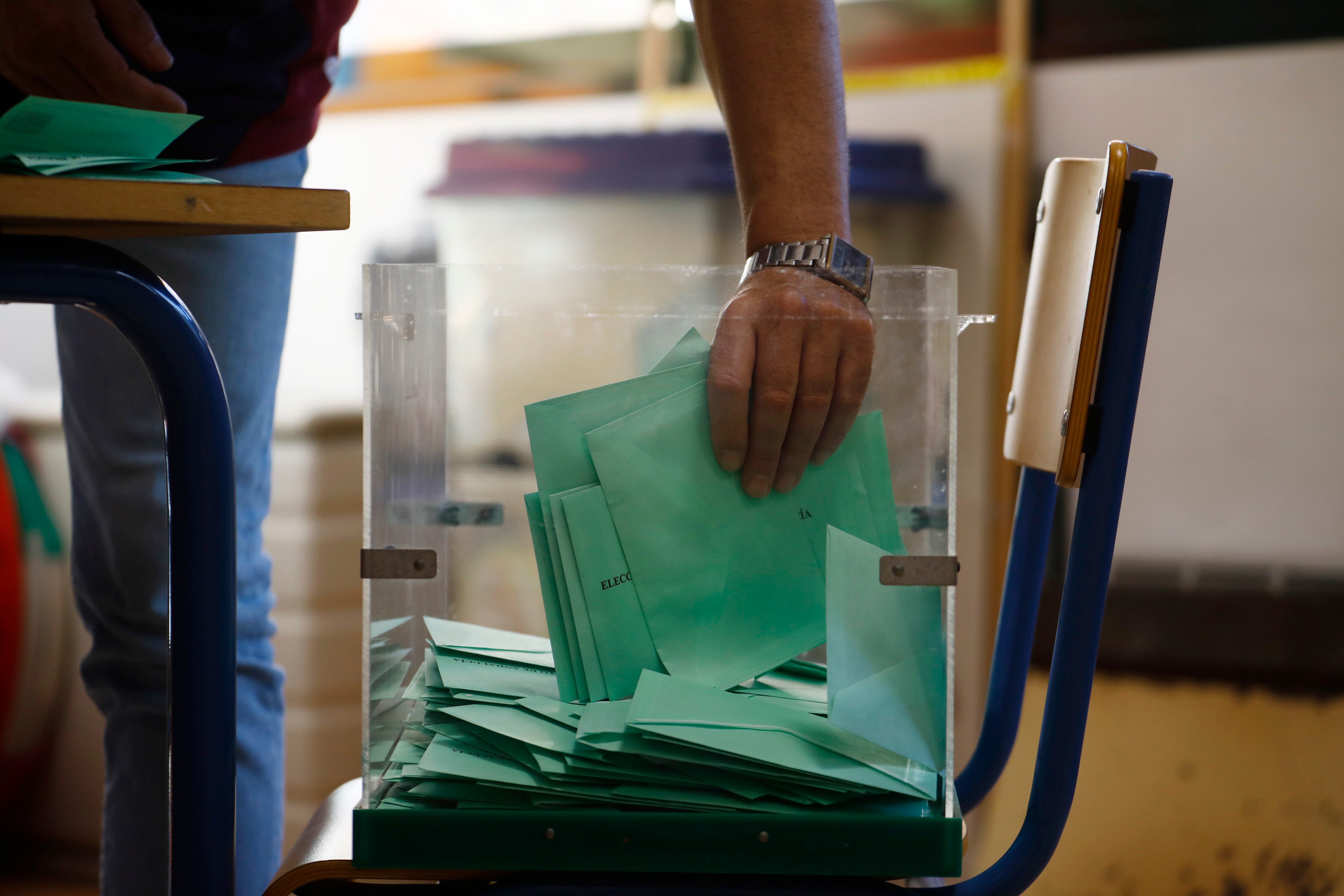 Una de las personas responsables recoge los votos de una urna para proceder al recuento de votos en un colegio electoral