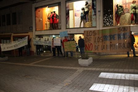 Un grupo de vecinos de Gomezserracín esperan con pancartas la salida del presidente de la Junta de un establecimiento de Cuéllar