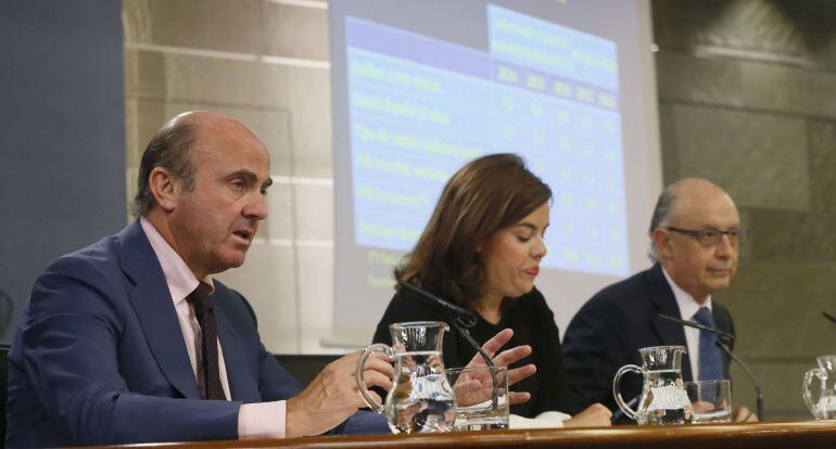 GRA257. MADRID, 10/07/2015.- El ministro de Economía y Competividad, Luis de Guindos (i), comparece junto a la ministra de la presidencia, vicepresidenta y portavoz, Soraya Saénz Santamaría (c) y el ministro de Hacienda y Administraciones Públicas, Cristo