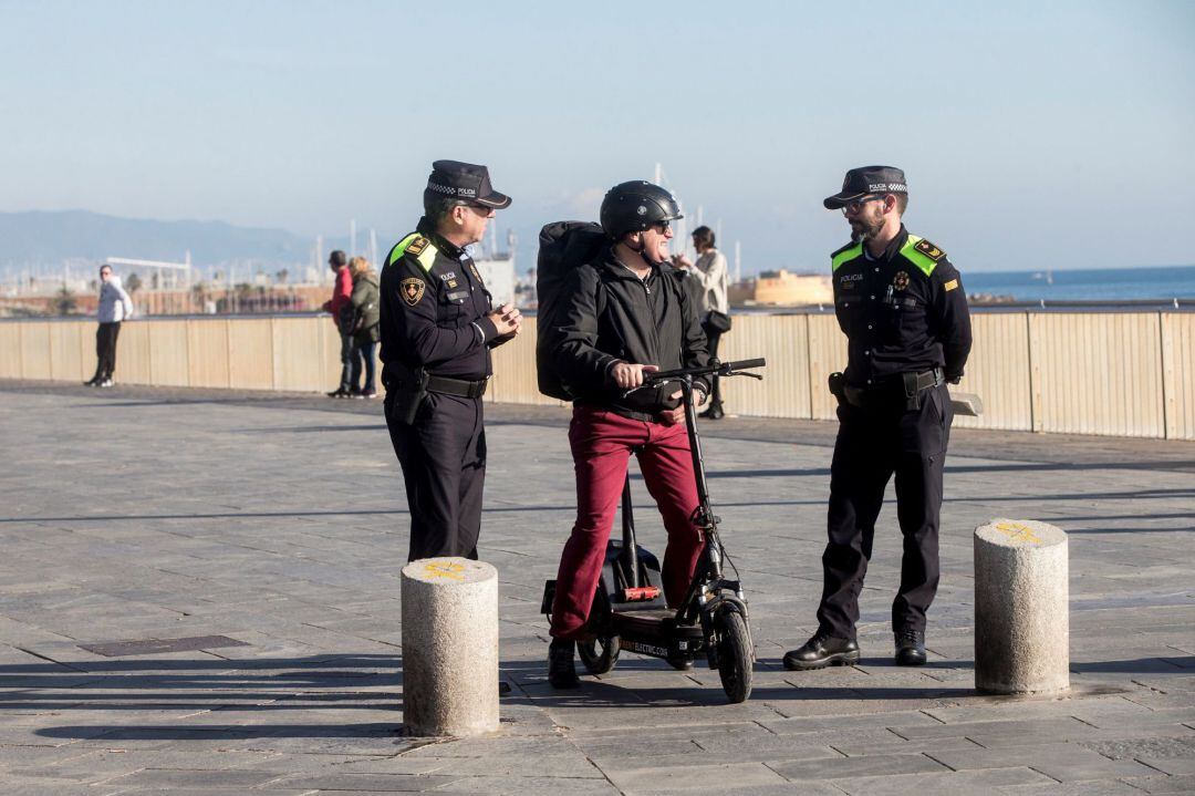 Usuario de un patinete eléctrico en Barcelona, con agentes de la Guardia Urbana