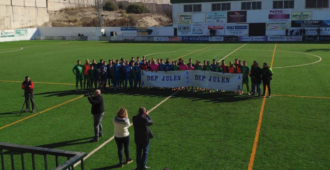 Jugadores de Mancha Real y El Palo sostienen una pancarta antes de empezar el encuentro.