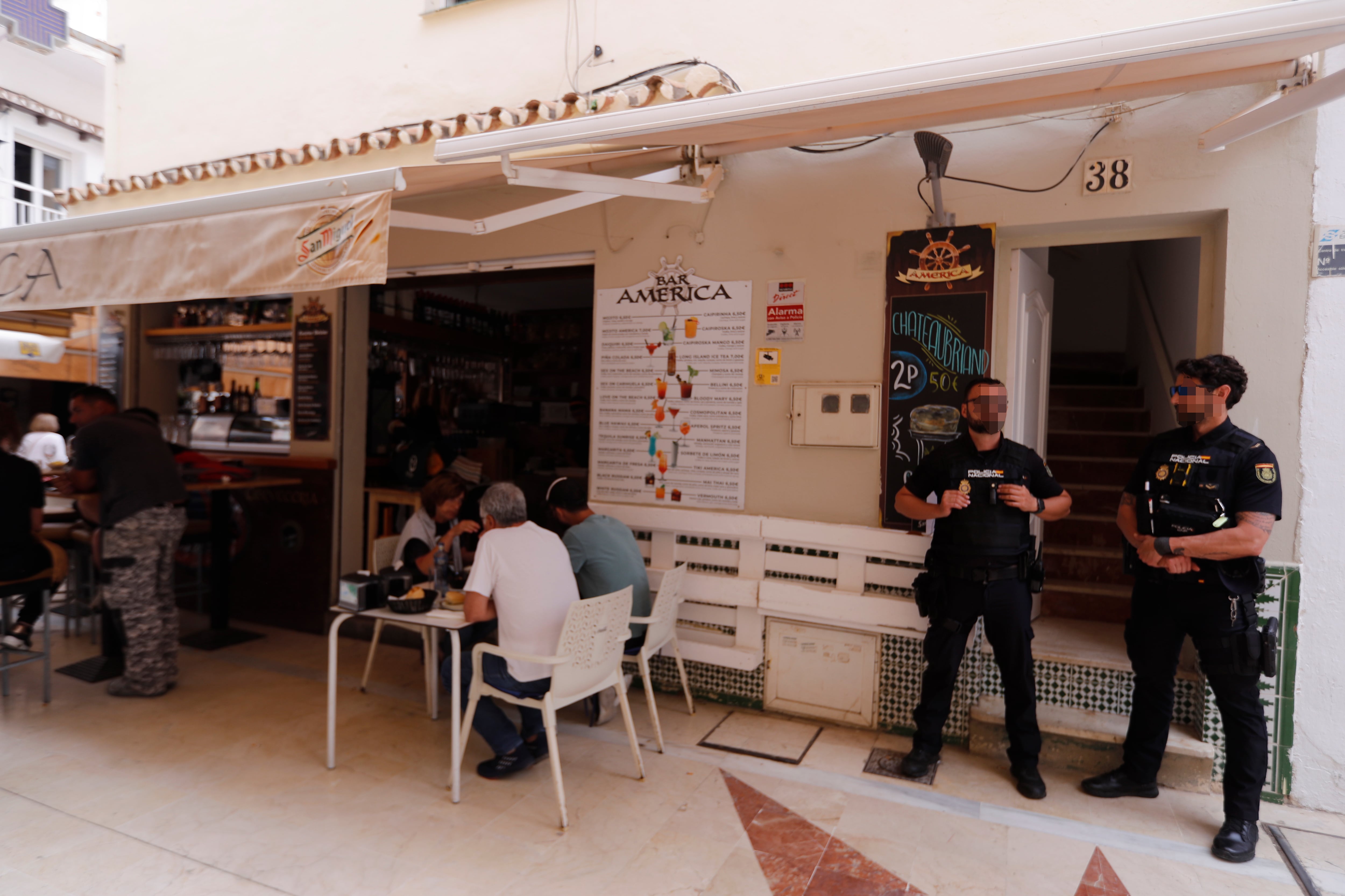 TORREMOLINOS (MÁLAGA), 17/05/2023.- Agentes de la Policía Nacional junto a la entrada de la vivienda número 38 de la calle San Ginés en Torremolinos (Málaga) donde ha sido encontrado el cadáver de una mujer de 28 años y junto al Bar América donde trabajaba, por lo que se busca a su pareja por presuntamente haberla apuñalado. EFE/ Jorge Zapata
