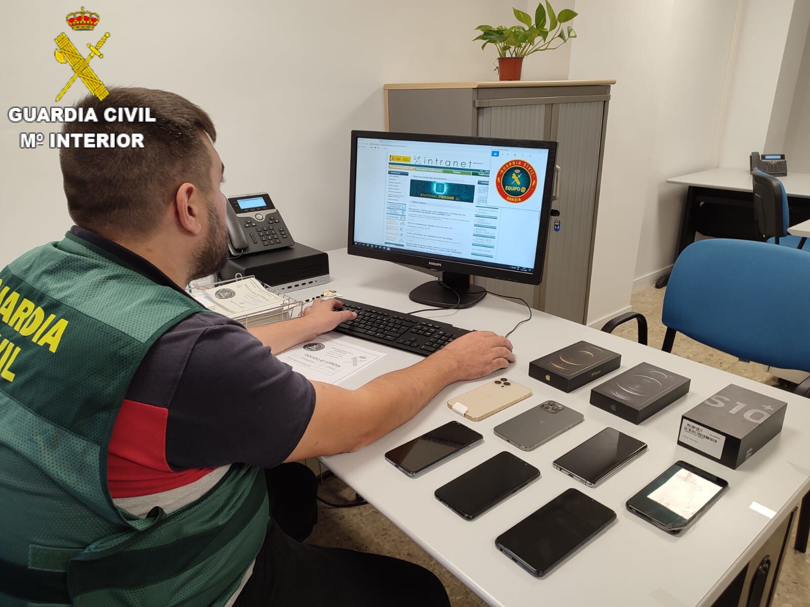 Un agente de la Guardia Civil junto algunos de los móviles utilizados en la estafa.