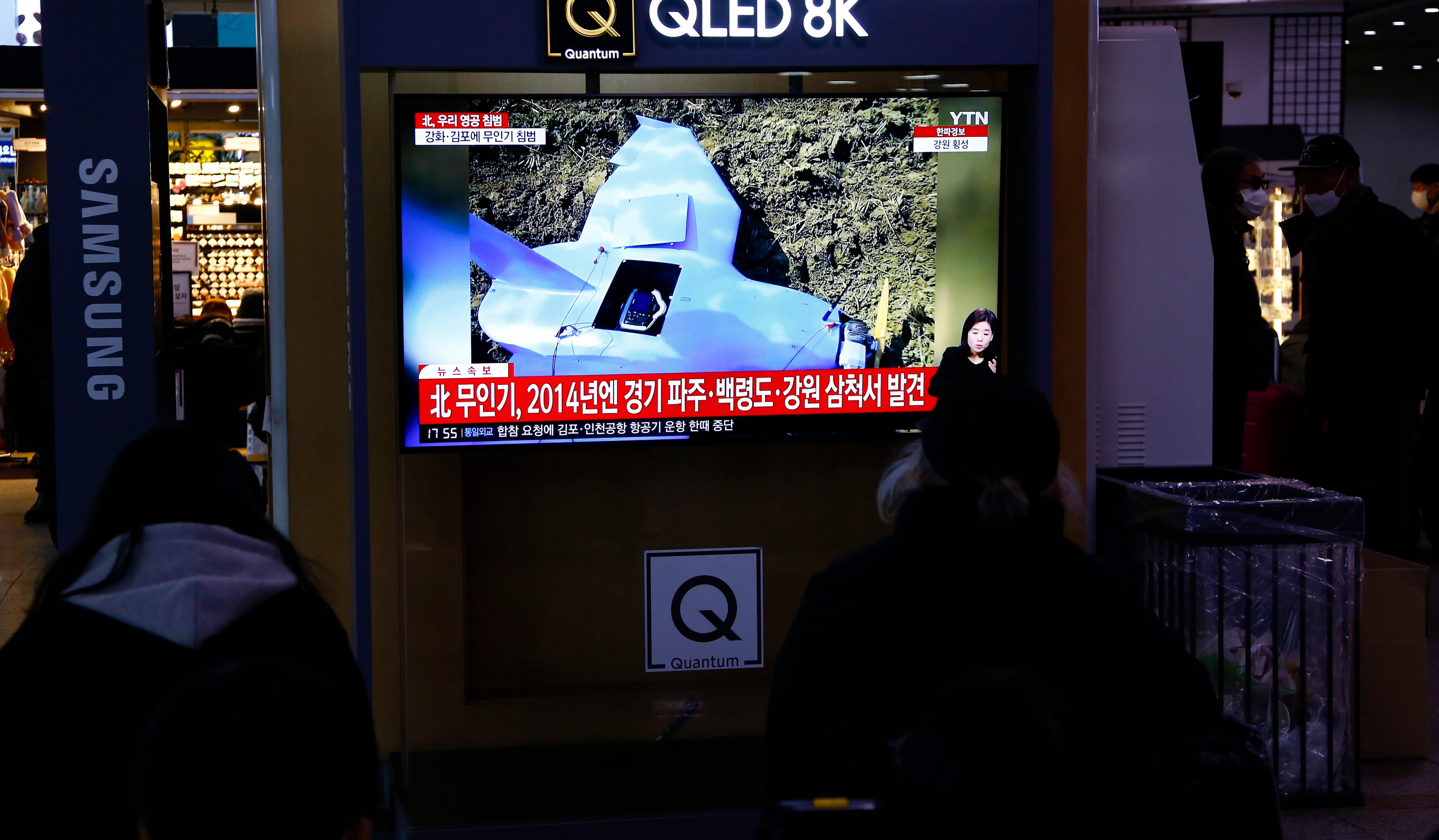 Varias personas ven en una televisión situada en una estación de Seúl (Corea del Sur) la noticia sobre la invasión del espacio aéreo del país con drones procedentes del Norte.