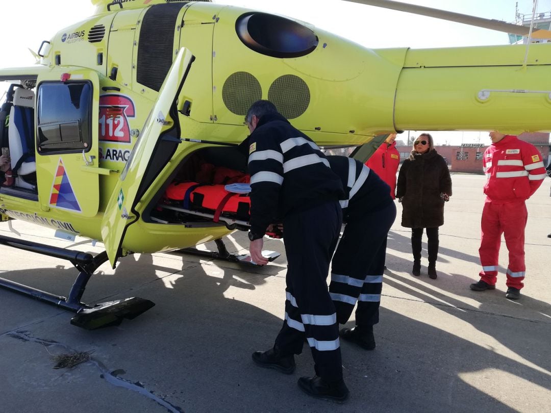 Pilotos del helicóptero del 112 entrando una de las camillas esta mañana en la base aérea de Zaragoza