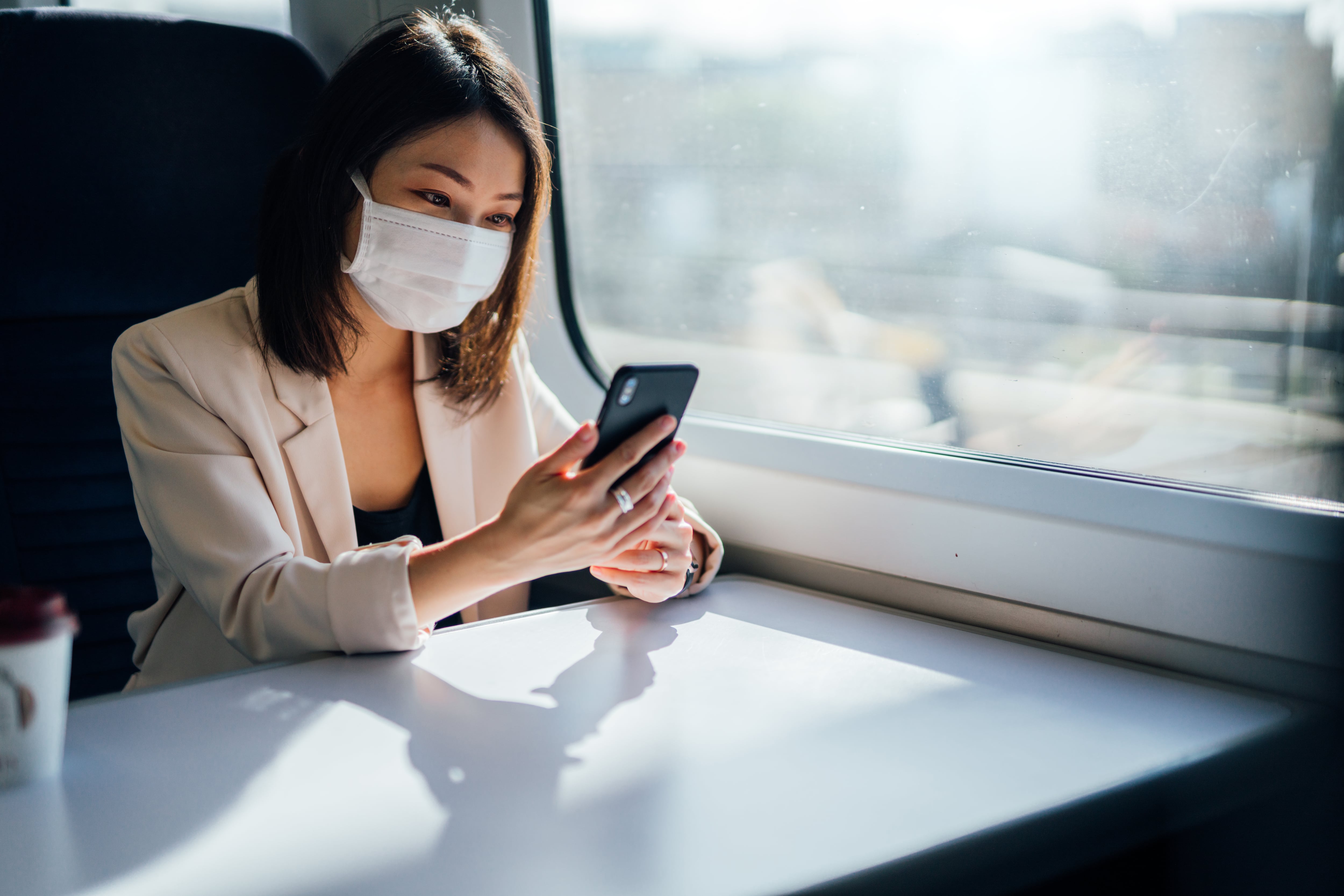 Una persona utiliza su teléfono móvil con la mascarilla puesta.