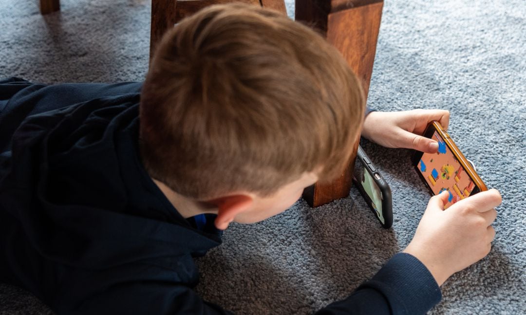 Un niño jugando a videojuegos en el móvil.