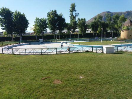 Un trabajador municipal realiza trabajos de limpieza en la piscina municipal