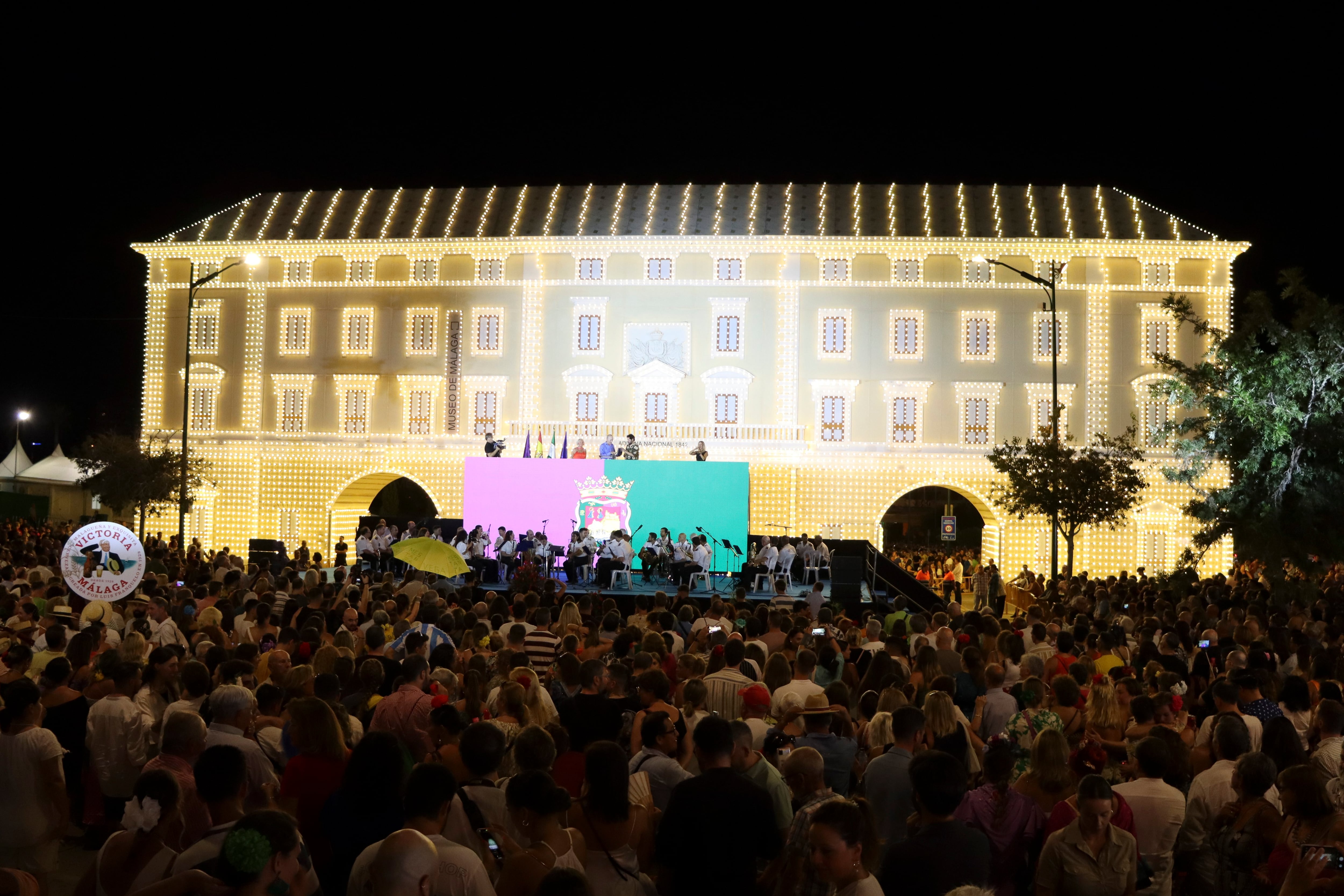 MÁLAGA (ESPAÑA), 17/08/2024.- Málaga ha dado este sábado el pistoletazo de salida oficial de su Feria de agosto con la lectura del pregón de las fiestas que ha realizado el cantautor Juan Gómez, El Kanka (c), y con el tradicional alumbrado artístico de la portada del recinto ferial del Real de Cortijo de Torres. EFE/ María Alonso
