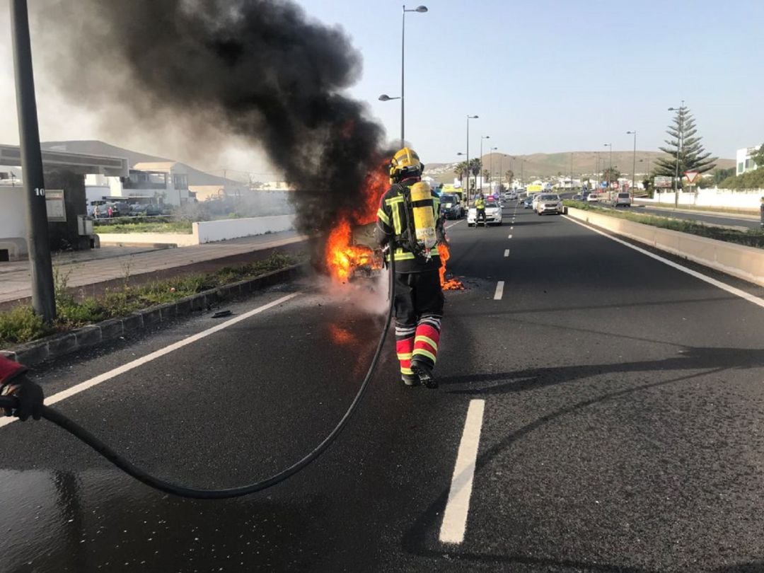 Los bomberos extinguiendo el fuego del vehículo incendiado.