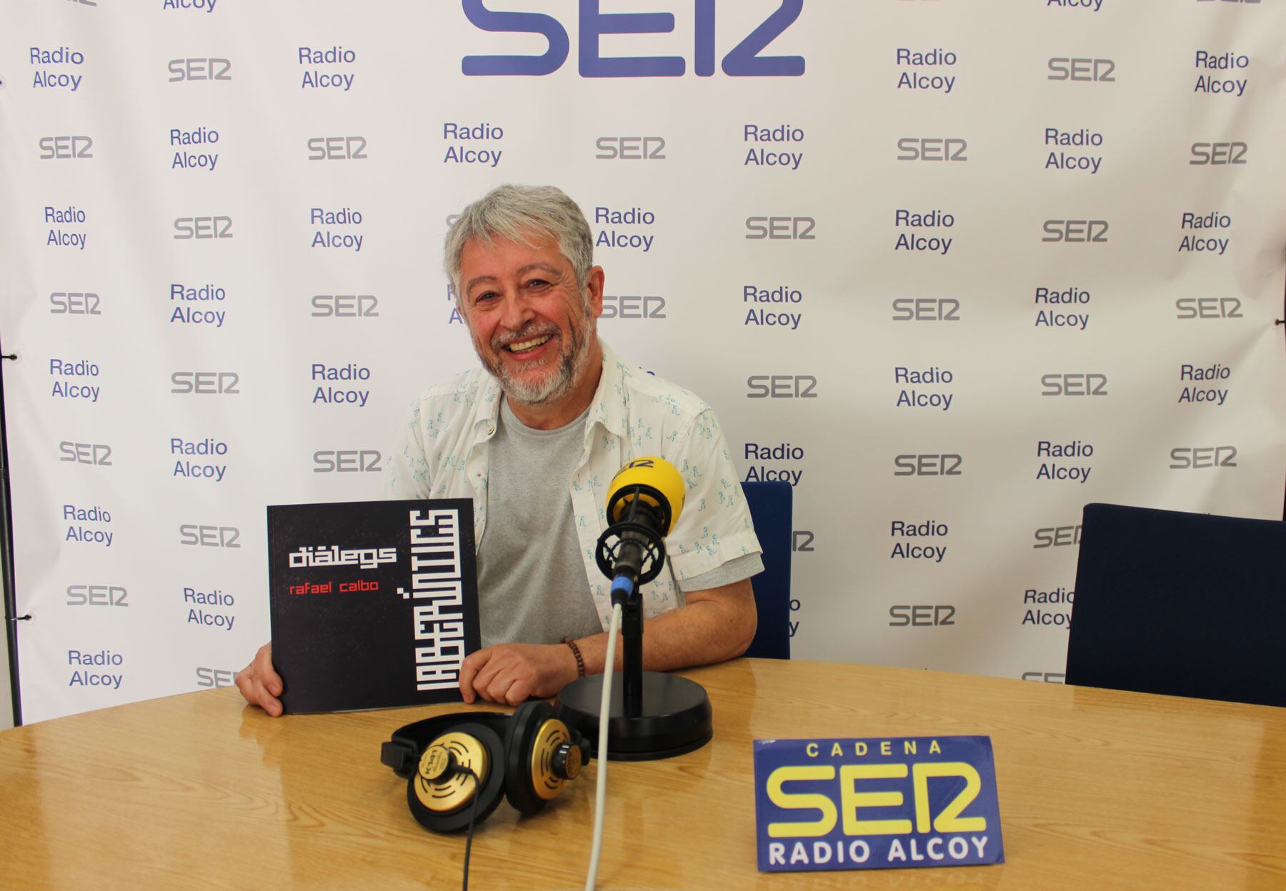 Rafa Calbo, en l'estudi de Radio Alcoy amb un exemplar del catàleg de la seua exposició