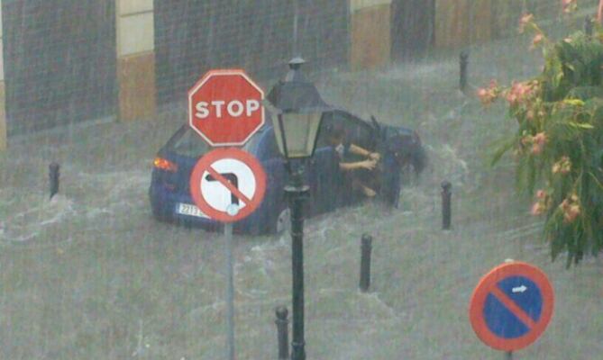 Un coche intenta avanzar por una de las calles del centro de Antequera durante las lluvias de esta tarde