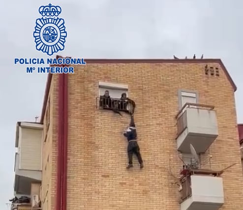 Los agentes de la Policía Nacional sujetan al hombre de una mano desde un tercer piso en la pedanía murciana de El Palmar