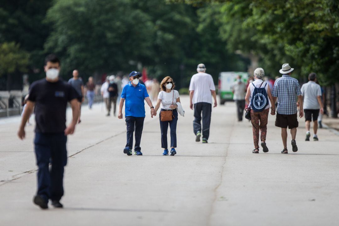 Varias personas pasean protegidas con mascarillas después de la reapertura del Parque de El Retiro.