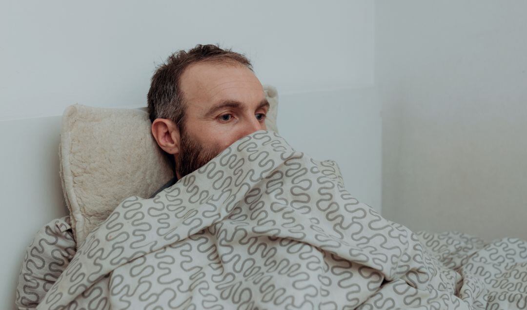 Un hombre permanece despierto en su cama.