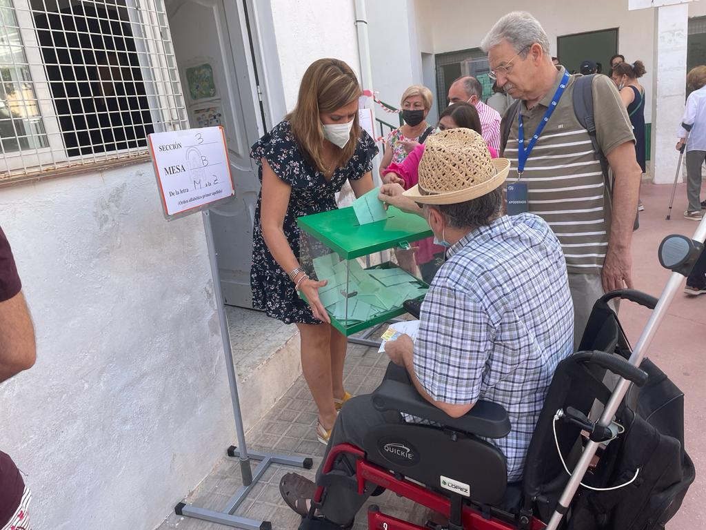 Una miembro de una mesa electoral saca la urna a la calle para que un anciano pueda votar en Jaén.