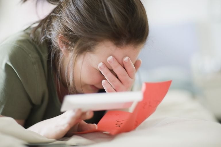 Una adolescente se tapa la cara mientras llora. 