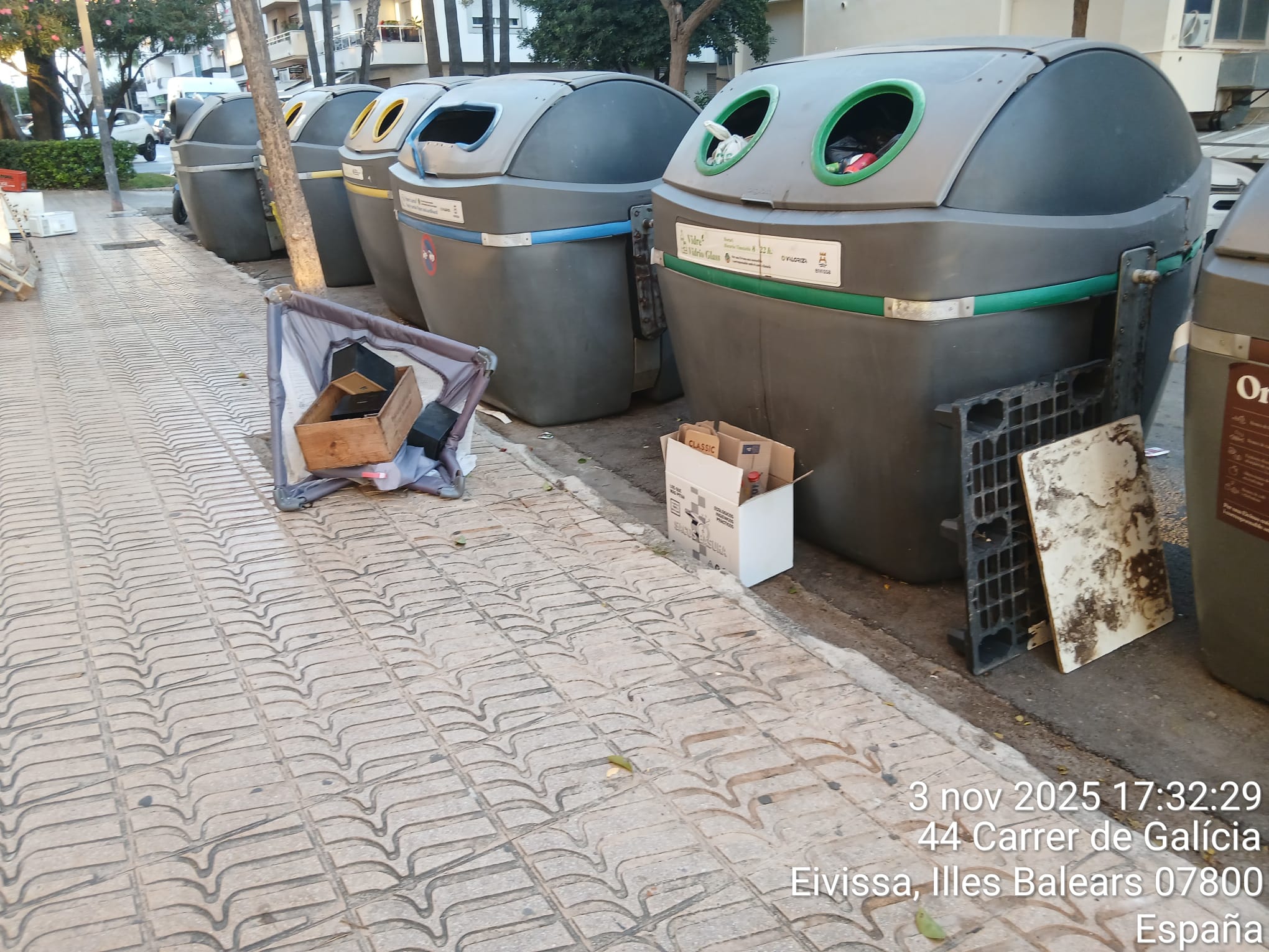 Contenedores de basura rodeados de residuos