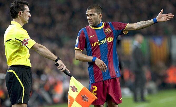 El defensa brasileño del FC Barcelona Daniel Alves (d) comenta una jugada con el juez de línea durante el partido correspondiente a la vigésimo cuarta jornada de Liga de Primera División que el conjunto azulgrana disputa contra el Athletic Club esta noche