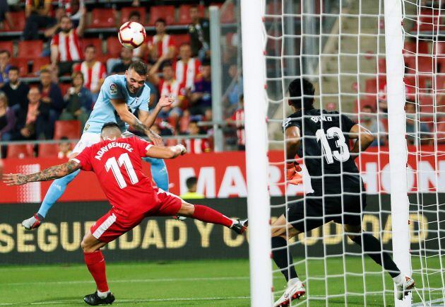 El delantero del Celta de Vigo Iago Aspas (i, arriba) cabecea un balón ante Aday Benítez y el portero Bono (d), ambos del Girona, durante el partido correspondiente a la cuarta jornada de LaLiga Santander disputado esta noche en el estadio de Montilivi, en Gerona.