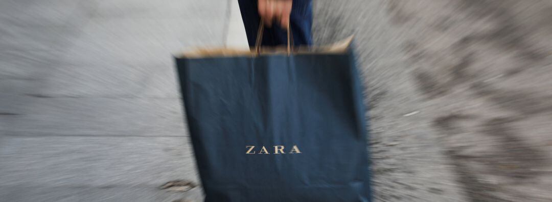 A mans hold a Zara shopping bag outside a Zara store