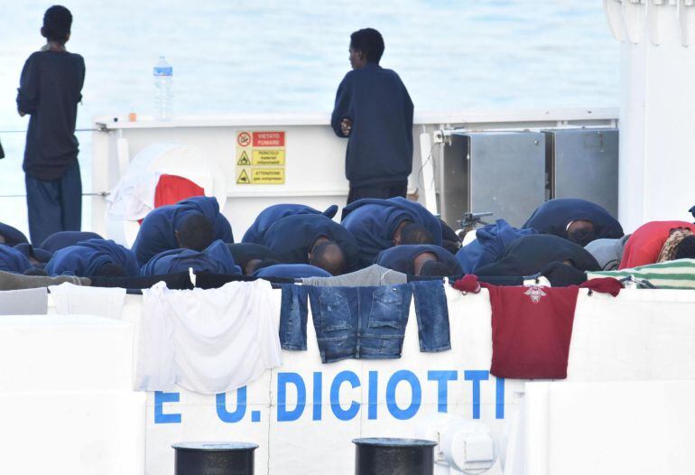 Migrantes rezan a la espera del desembarco del barco italiano de la Guardia Costera italiana en Catania, Italia.