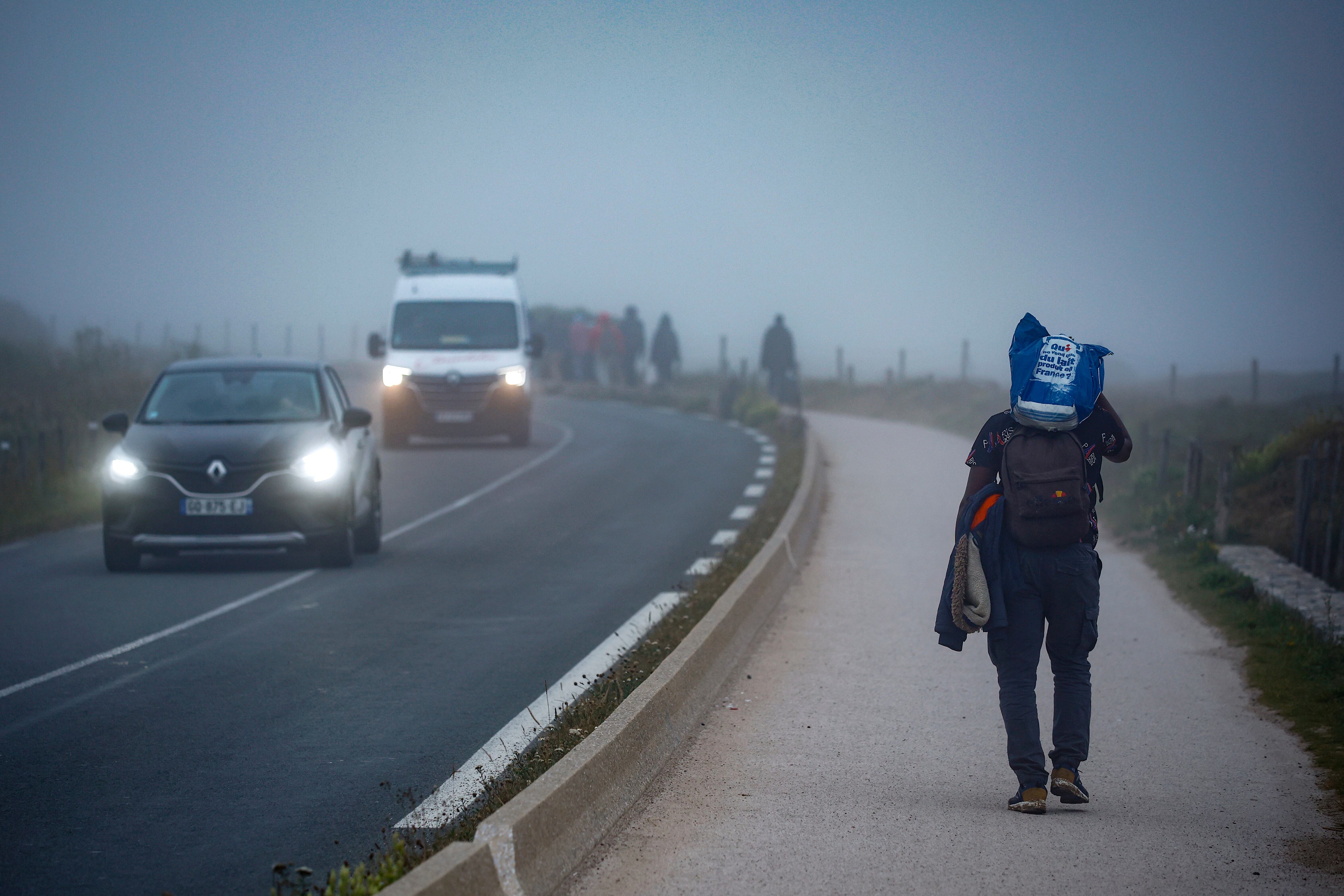Migrantes caminan por la carretera a primera hora de la mañana tras intentar cruzar el Canal de la Mancha a las afueras de Wimereux, al norte de Francia