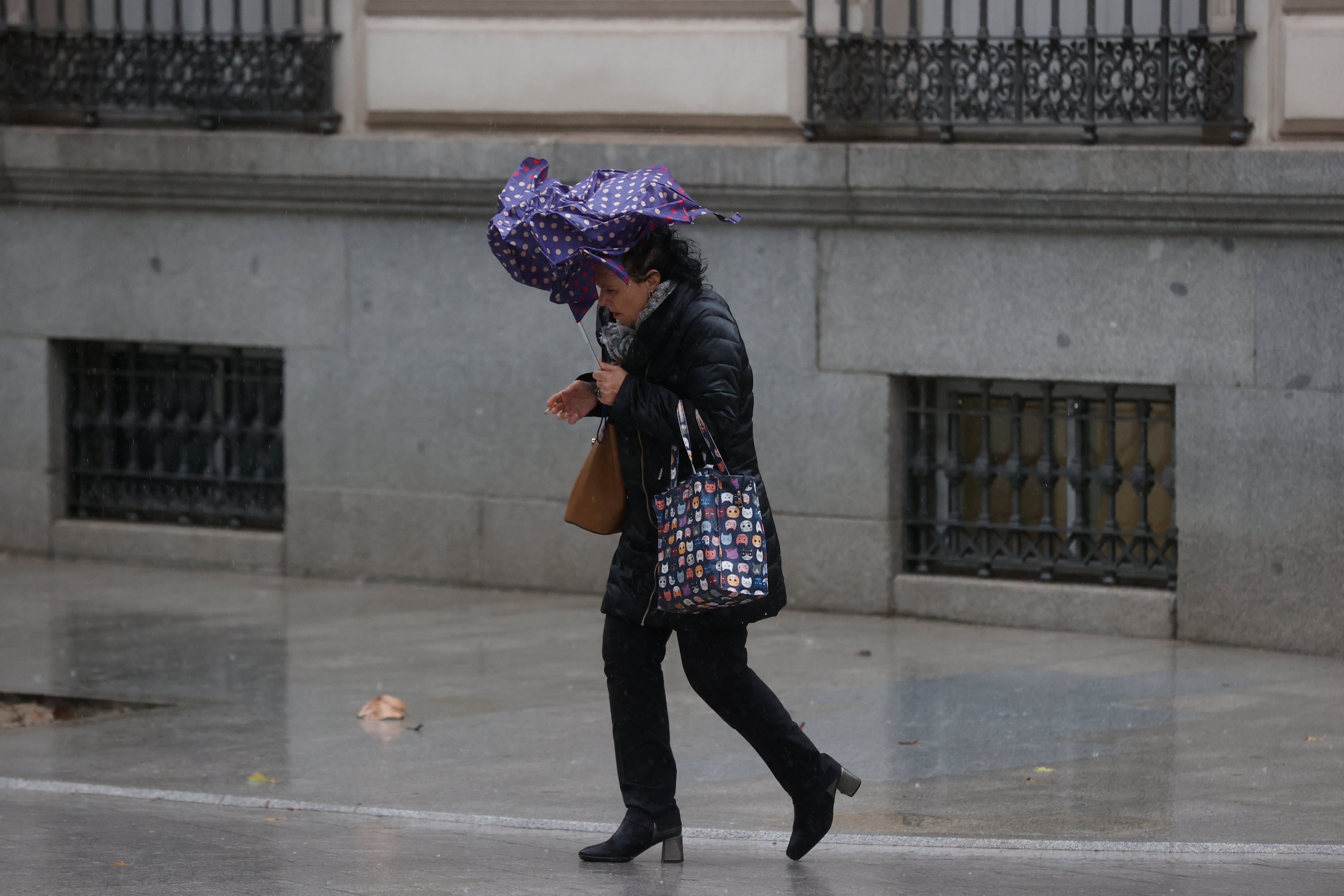 Una viandante se enfrenta a las fuertes rachas de viento mientras camina