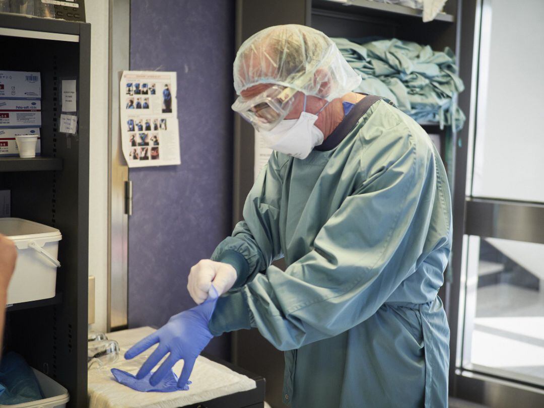 Un trabajador sanitario se coloca un guante en las instalaciones pertenecientes a la UCI de la Clínica Universidad de Navarra