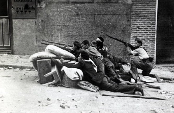 Unac milicia abre fuego contra los rebeldes, armados con rifles desde el refugio de una barricada levantada a toda prisa durante la Guerra Civil española