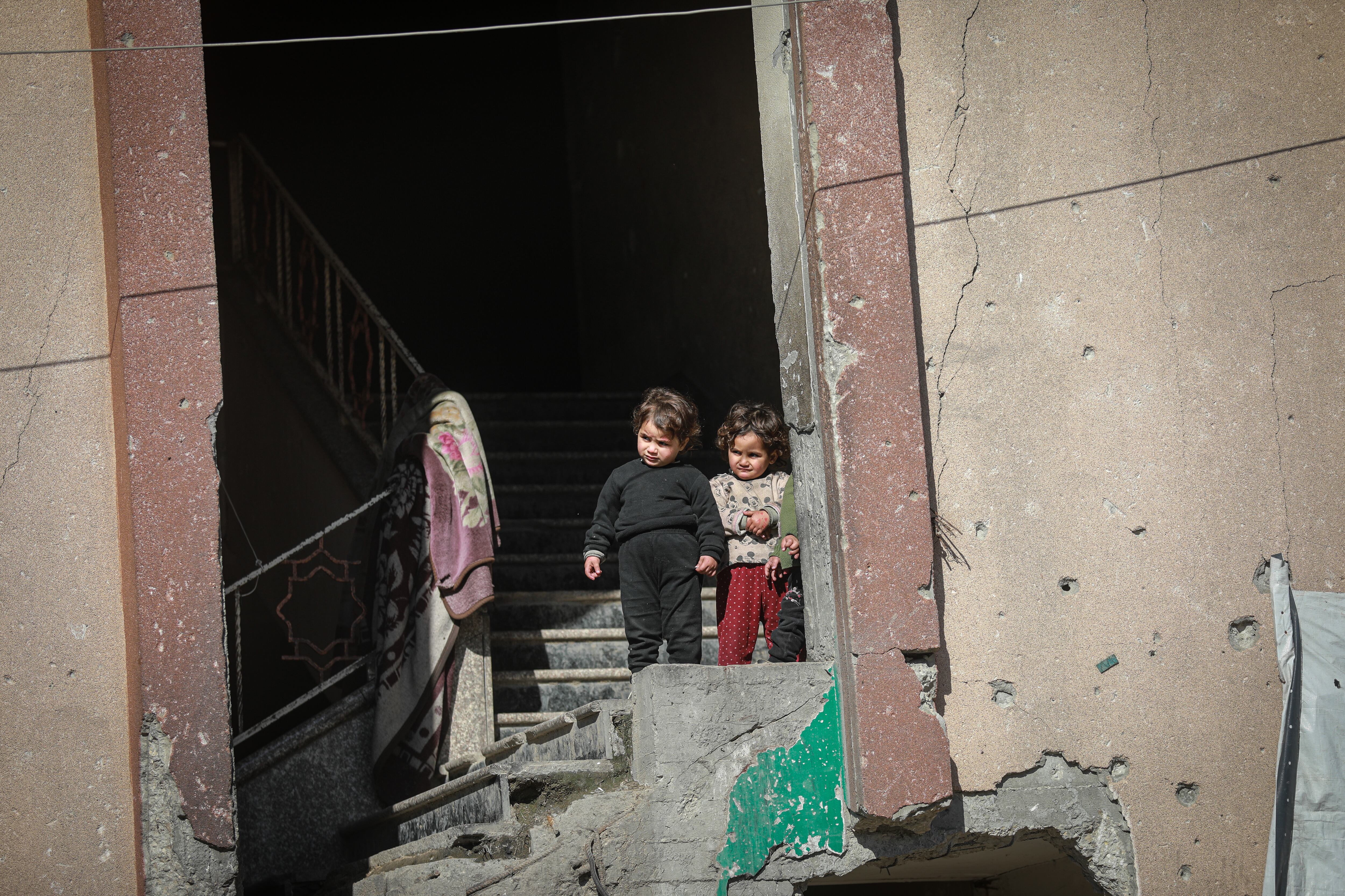 Dos niños se asoman por un edificio parcialmente destrozado en Gaza.