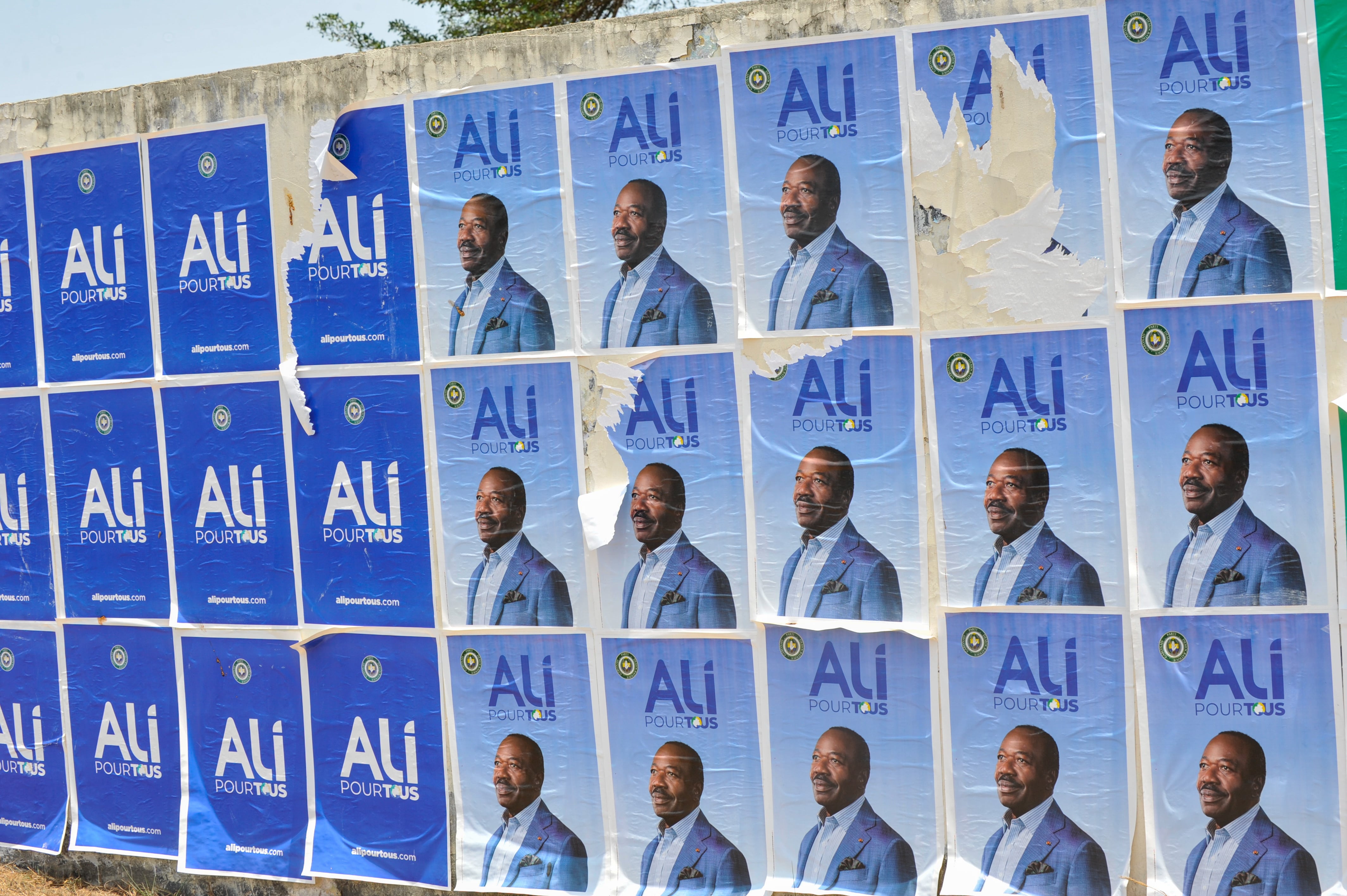 Carteles del derrocado presidente Ali Bongo Ondimba se exhiben en una pared en Libreville, Gabón, 31 de agosto de 2023.