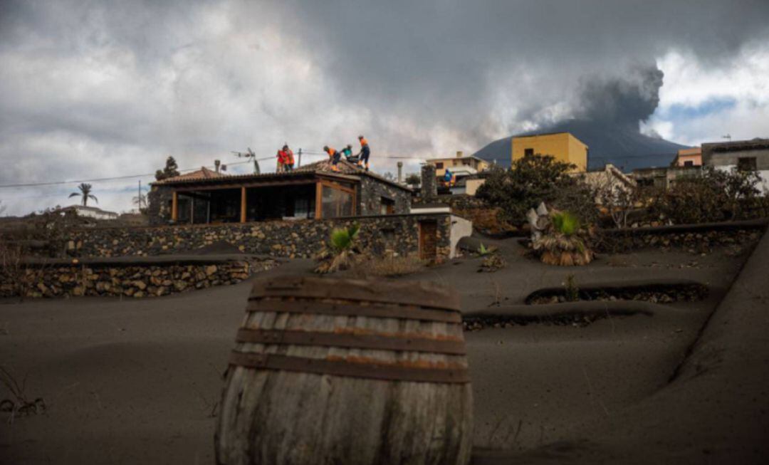 Varios voluntarios limpian la ceniza de los tejados de sus casas, afectados por la erupción volcánica en La Palma.