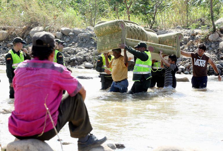 BOG07. CÚCUTA (COLOMBIA), 28/08/2015.- Un grupo de colombianos, con ayuda de miembros de la Policía Nacional, pasa sus pertenencias por el río Táchira desde Venezuela hoy, viernes 28 de agosto de 2015, hacia el lado de Colombia en la frontera. El miedo a 