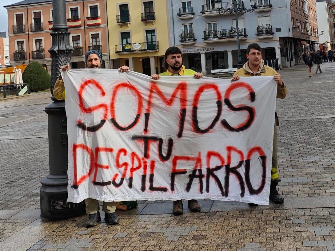 Los trabajadores del operativo antiincendios tras la pancarta