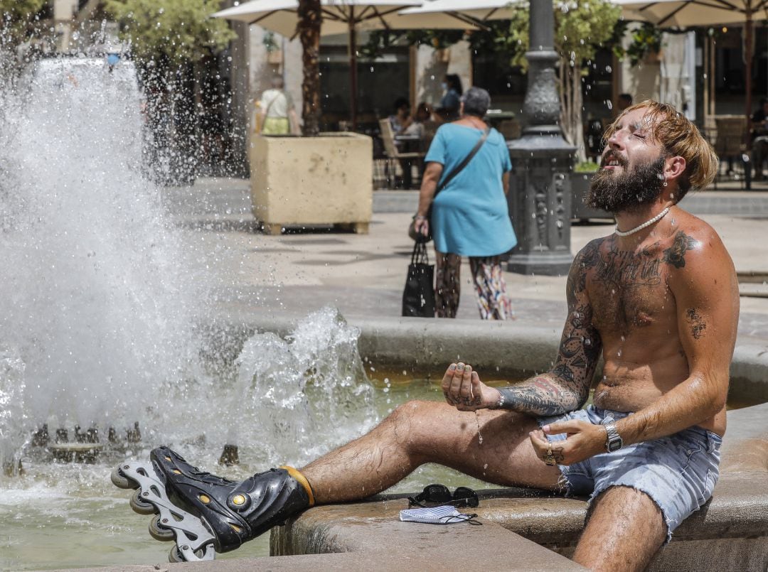 Un hombre se refresca en una fuente.