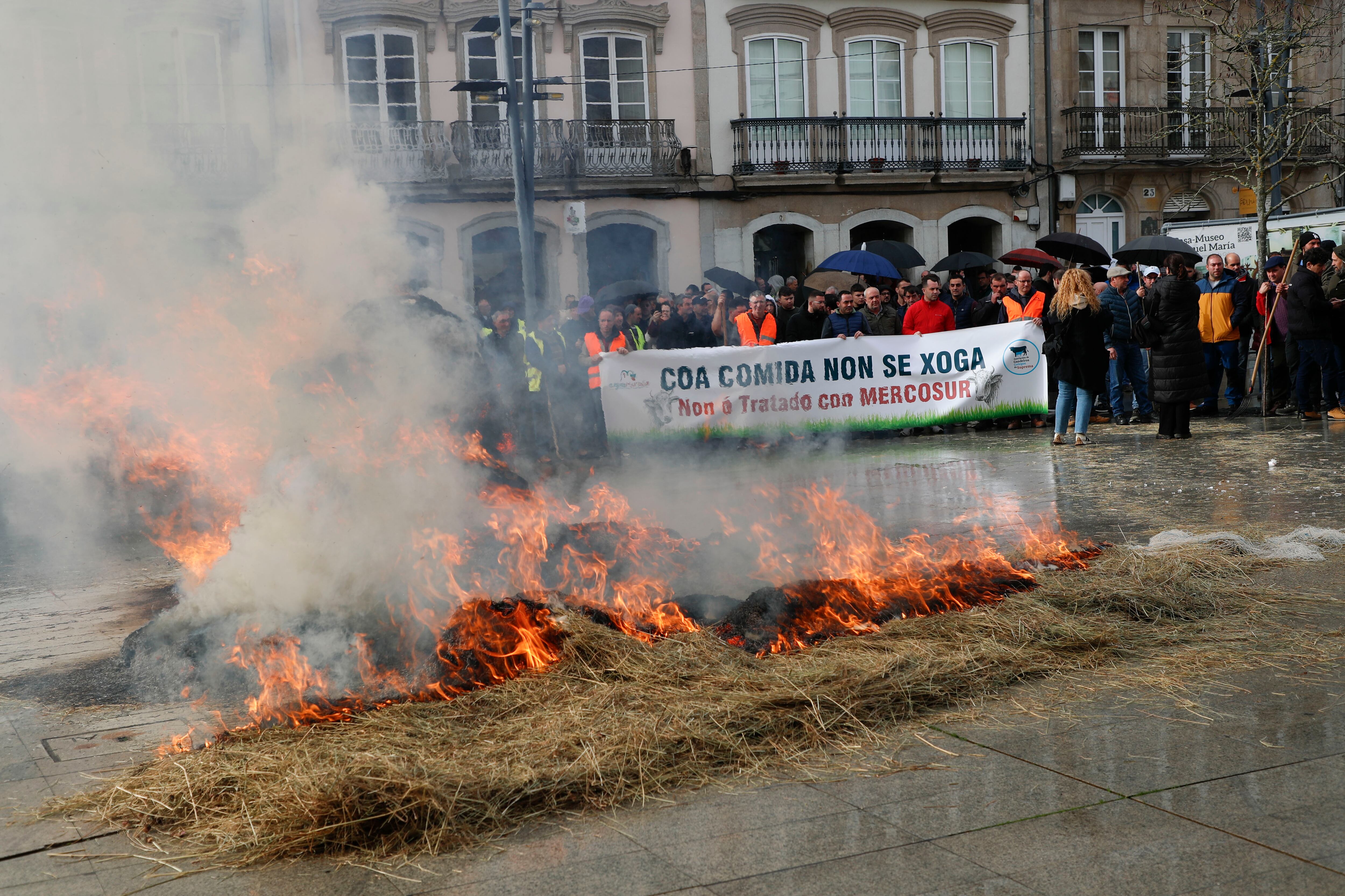 LUGO, 14/01/2026.-Quema de paja a las puertas de la Diputación Provincial de Lugo durante la protesta de agricultores contra el tratado comercial de la Unión Europea con Mercosur. Por segundo día consecutivo, decenas de tractores volvieron a provocar este martes retenciones y atascos en el centro de Lugo, con motivo de esa protesta convocada por las organizaciones Agromuralla -que agrupa a productores de leche de las provincias de Lugo y A Coruña- y Gandeiros Galegos da Suprema -ganaderos que producen carne de Ternera Gallega Suprema-. EFE/ Pedro Eliseo Agrelo Trigo