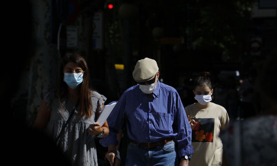 Personas con mascarilla caminan por una calle.