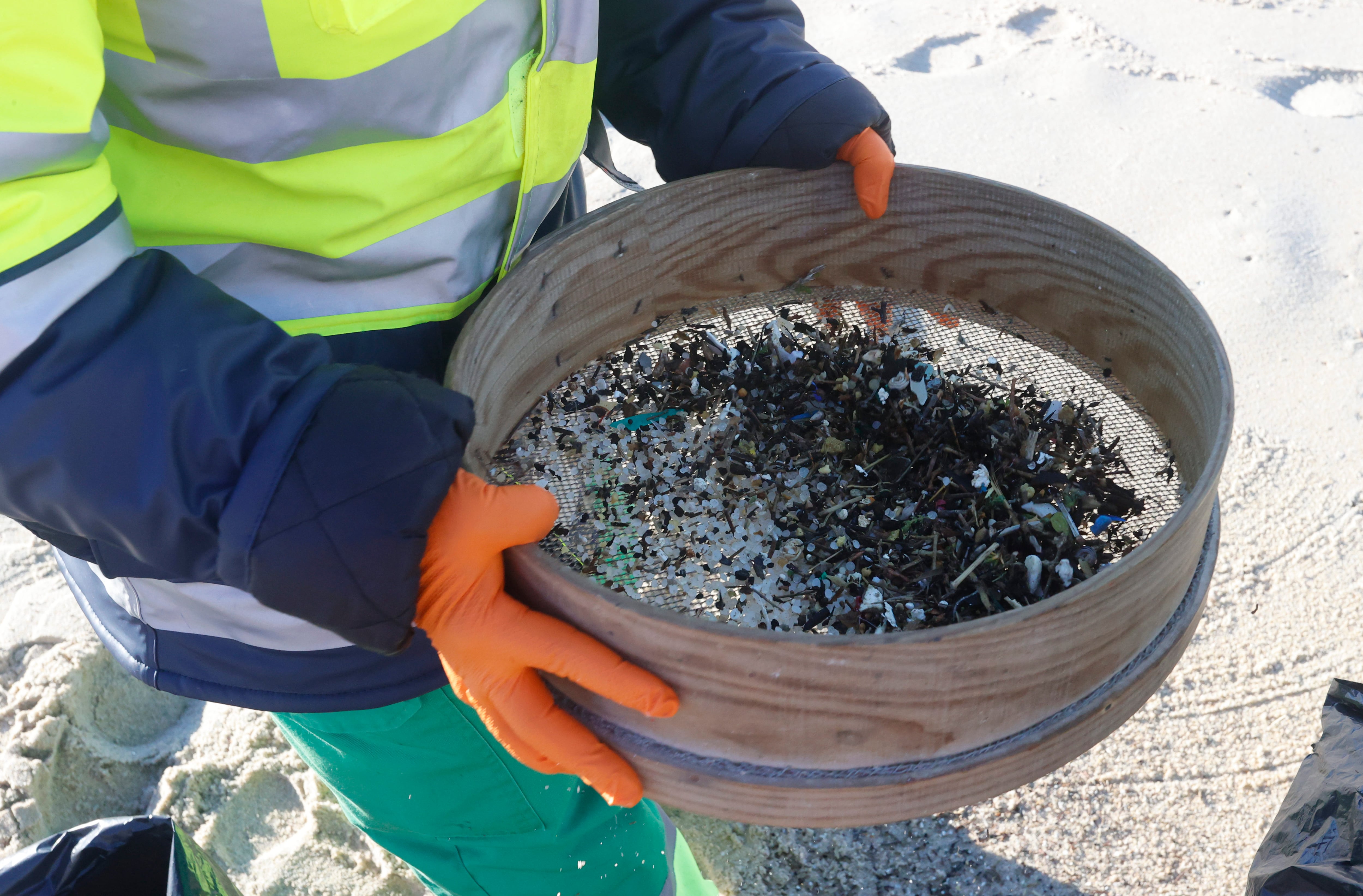 FERROL, 12/01/2024.- Una persona recoge pellets este viernes en las costas de Ferrol, en una jornada en la que continúa la llegada a los arenales gallegos de estas pequeñas esferas de plástico tras la caída de un contenedor del buque Toconao el pasado mes de diciembre. EFE/Kiko Delgado
