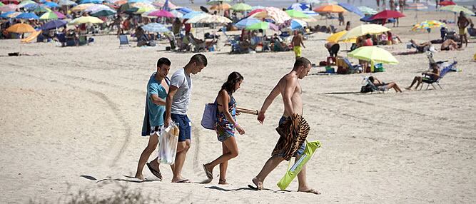 Jóvenes llegan a la playa de La Barrosa en Chiclana (Cádiz), una solución para aliviar el calor que estos días azota España