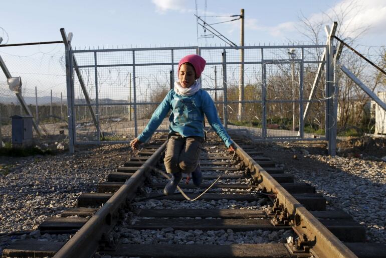 Un iño salta a la comba sobre una vía de tren frente a la frontera griega con Macedonia