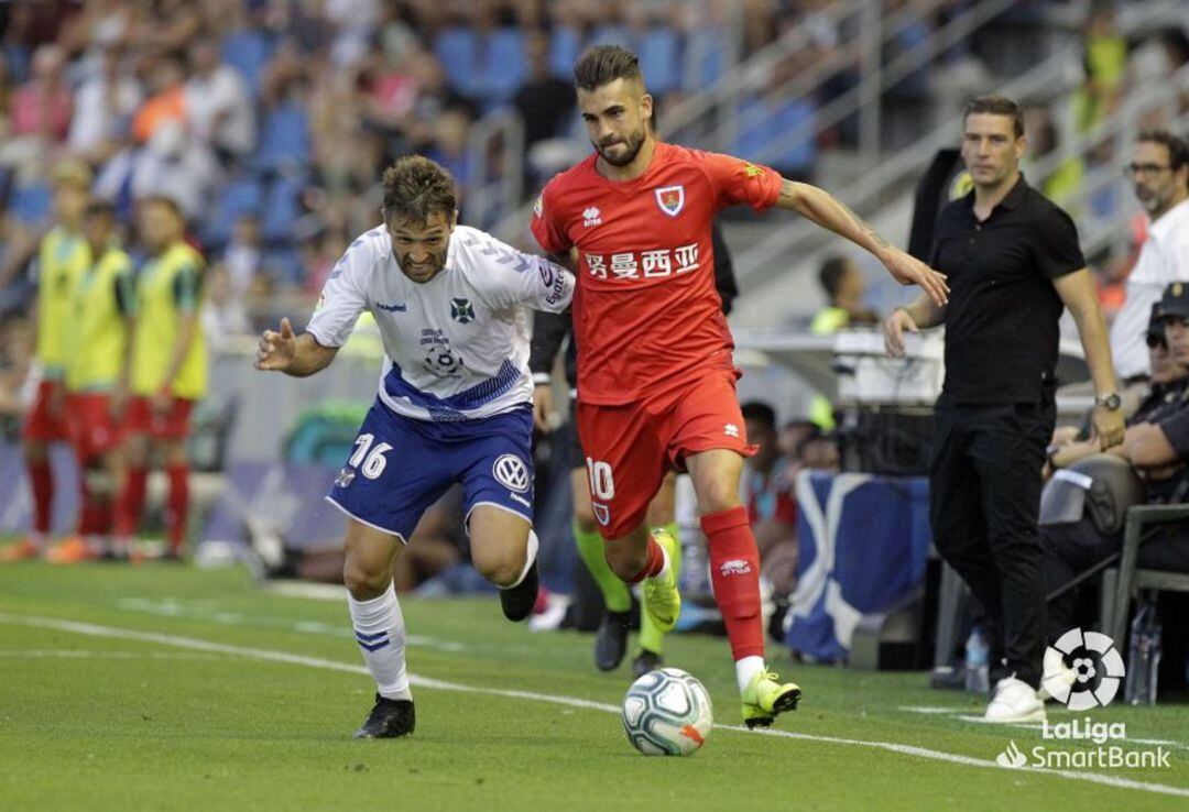 Oyarzun conduce el balón con la presión de Aitor Sanz.