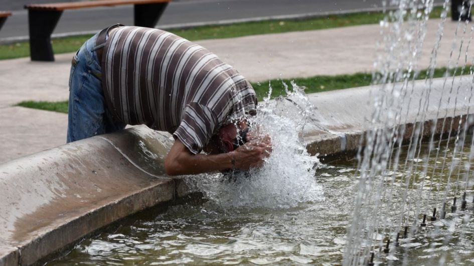 Un hombre se remoja la cabeza en una fuente.