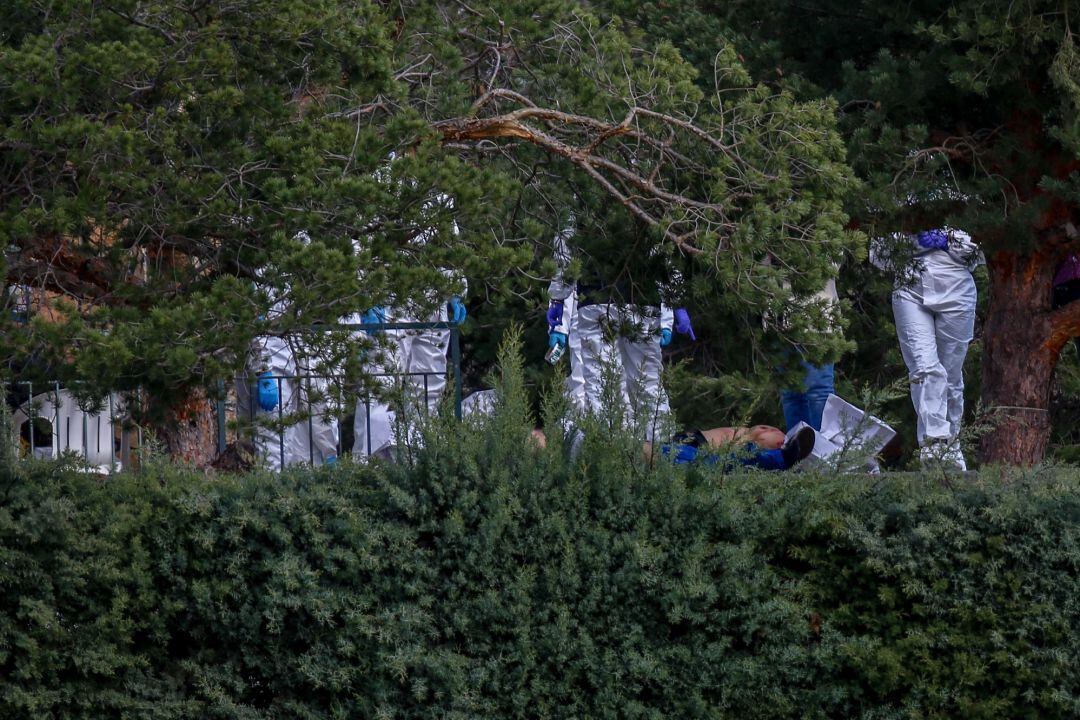 Varios médicos forenses alrededor de los cuerpos de los fallecidos en un incendio en una casa de El Molar, Madrid.