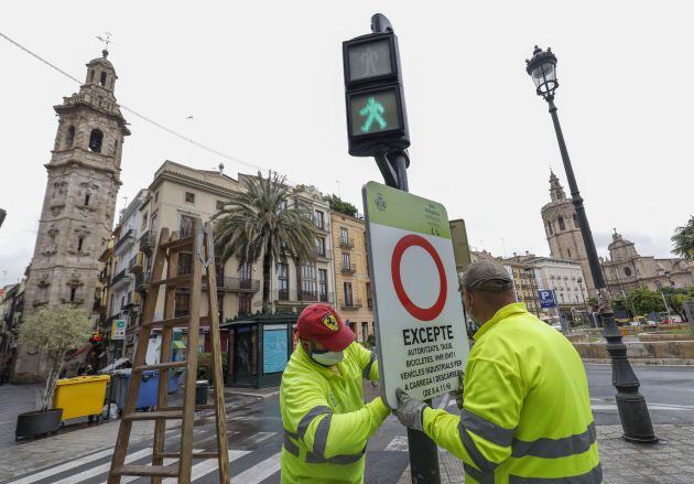 Dos obreros colocan una señal en la plaza de la Reina para las obras de peatonalización